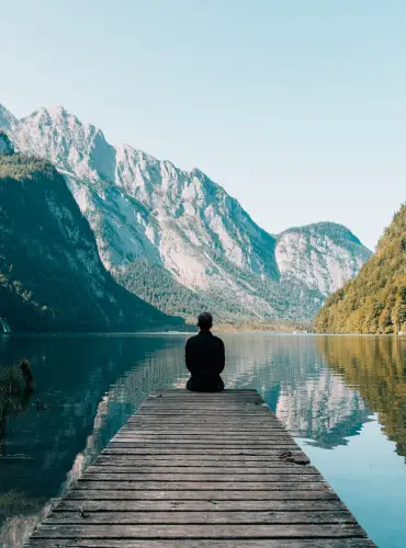 Person sitting on dock by lake